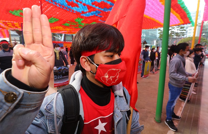 아웅산 수치 국가 고문의 민주주의민족동맹(NLD) 당기를 든 한 미얀마인이 지난 21일 서울 종로구 조계사 일주문 앞에서 열린 미얀마 민주주의 회복을 위한 기자회견에 참석해 세손가락 경례를 하고 있다.(사진/뉴시스)